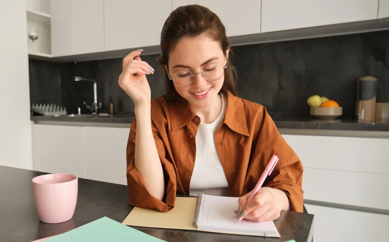 Personne souriante écrivant dans un journal, illustrant l'application du mindset positif